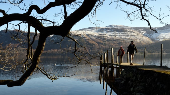 Looking out at the jetty at Brandelhow where two people are walking back on a clear winter's day